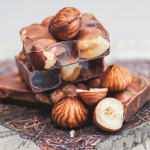 Close-up of stacked chocolate bars with whole hazelnuts, perfect for sweet indulgence.