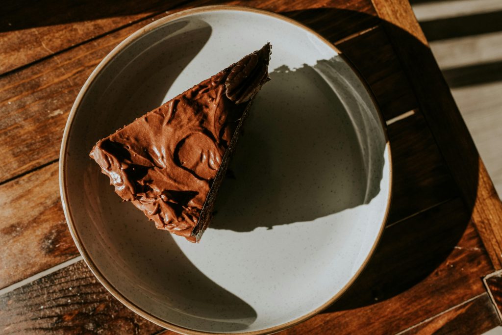 Appetizing slice of chocolate cake on a rustic wooden table, perfect for dessert themes.
